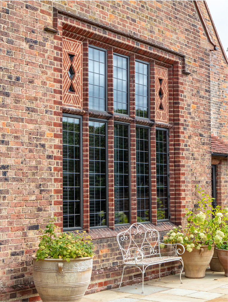 Bay of bronze leaded windows in decorative brickwork